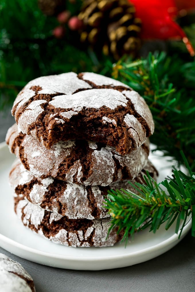 Chocolate Crinkle Cookies Recipe #cookies #chocolate #christmas #dessert #baking #edsug A stack of chocolate crinkle cookies with a bite taken out of one.