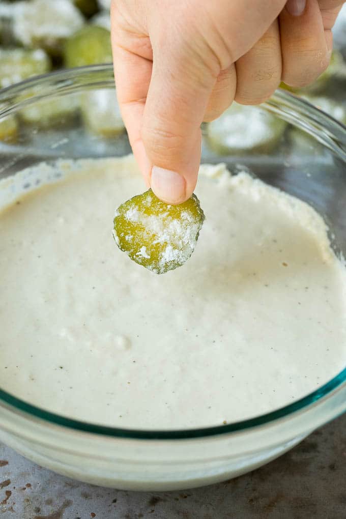 Fried Pickles Recipe #pickles #appetizer #snack #edsug A slice being dipped into a bowl of beer batter.