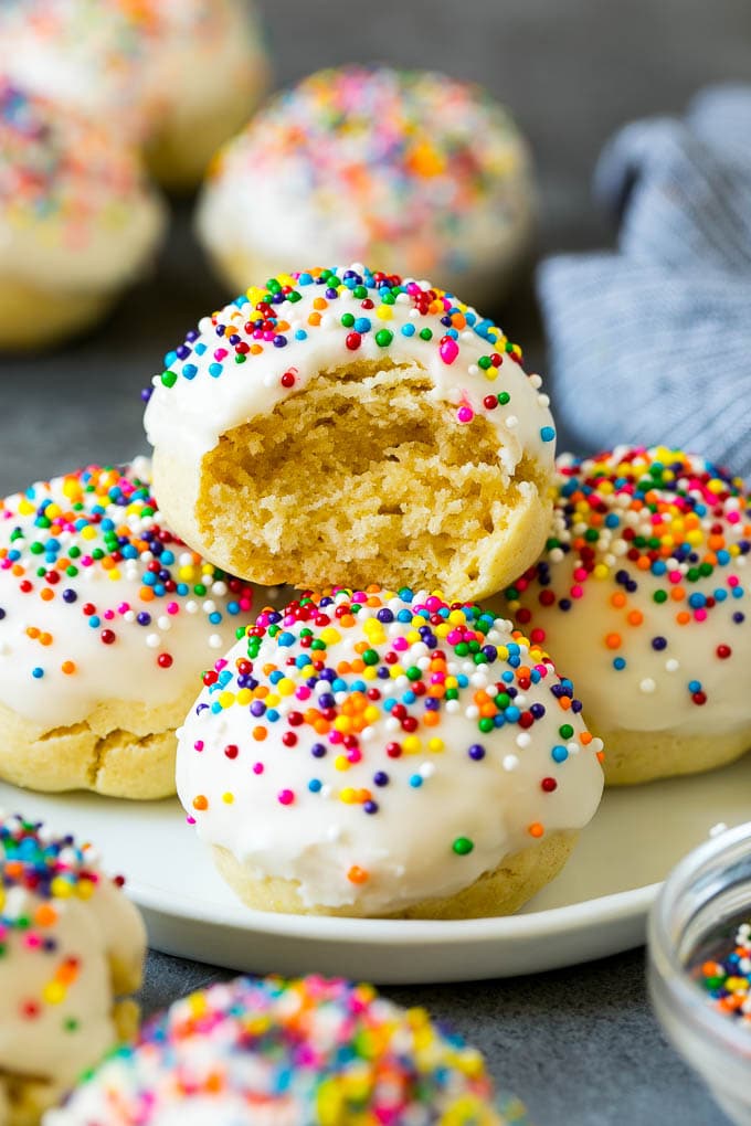 Italian Cookies Recipe | Almond Cookies #cookies #italianfood #frosting #sprinkles #baking #christmas #edsug A plate of Italian cookies with a bite taken out of one.