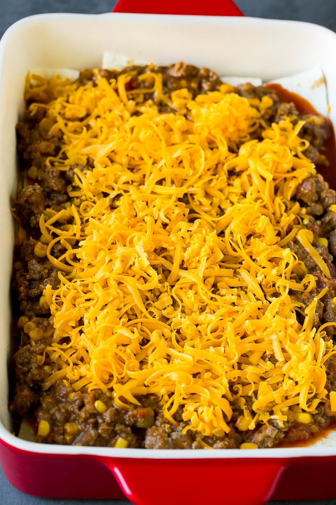 Mexican Lasagna Recipe | Mexican Casserole #mexican #lasagna #groundbeef #beans #dinner #cheese #edsug Layers of tortillas, ground beef and shredded cheese in a baking dish.