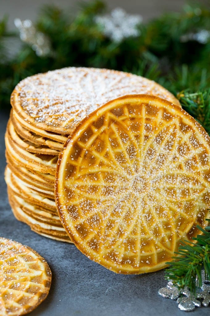 Pizzelle Cookies Recipe #cookies #baking #dessert #christmas #edsug A stack of pizzelle cookies dusted with powdered sugar.