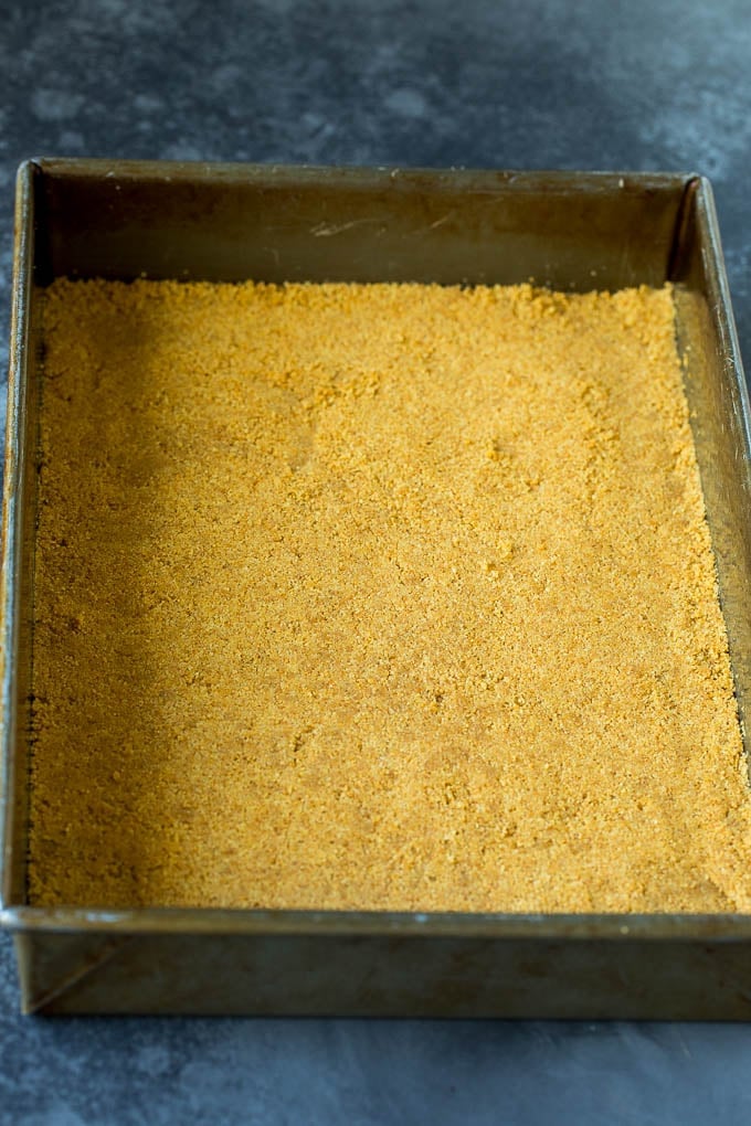 These pumpkin cheesecake bars are layers of graham cracker crust, vanilla cheesecake and pumpkin cheesecake, all baked together to create an impressive dessert. Graham cracker crust in a baking dish.