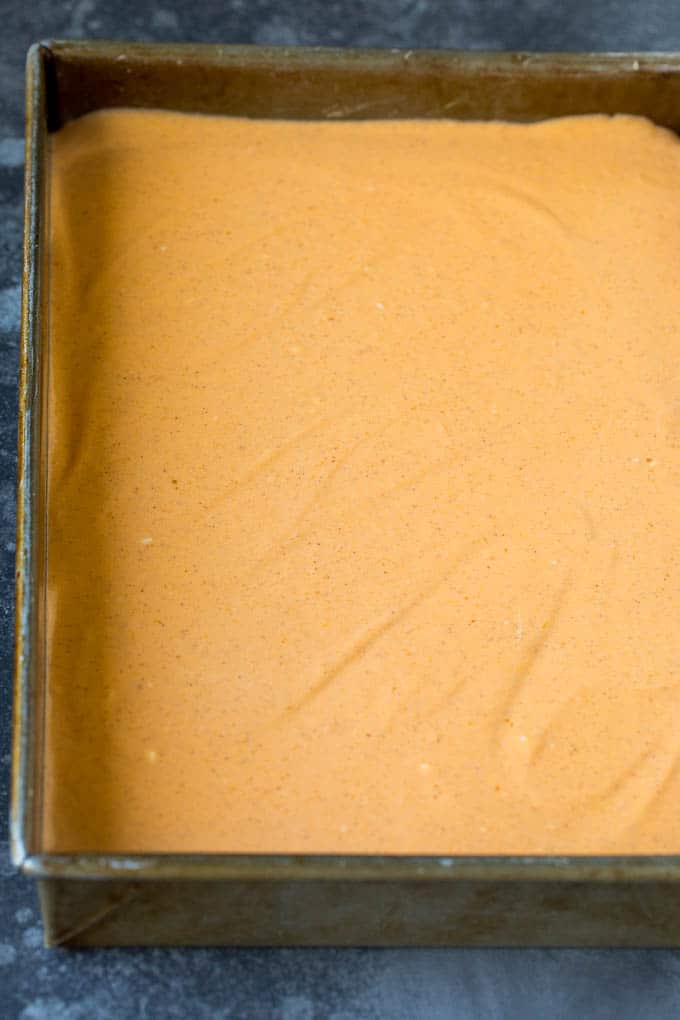 These pumpkin cheesecake bars are layers of graham cracker crust, vanilla cheesecake and pumpkin cheesecake, all baked together to create an impressive dessert. A layer of pumpkin cheesecake batter in a rectangular pan.