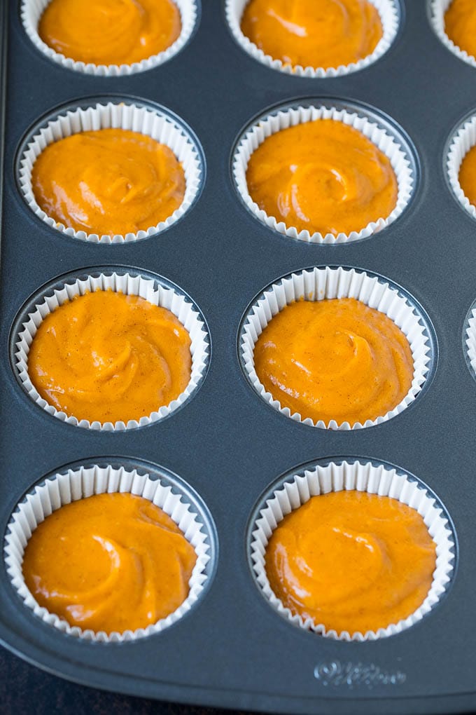 Pumpkin Cupcakes Recipe | Pumpkin Cake #cake #cupcakes #pumpkin #frosting #baking #fall #thanksgiving #edsug Batter inside paper cups in a muffin tin.