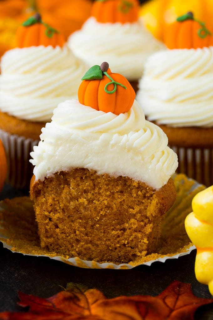 Pumpkin Cupcakes Recipe | Pumpkin Cake #cake #cupcakes #pumpkin #frosting #baking #fall #thanksgiving #edsug A pumpkin cupcake cut in half, surrounded by fall decorations.