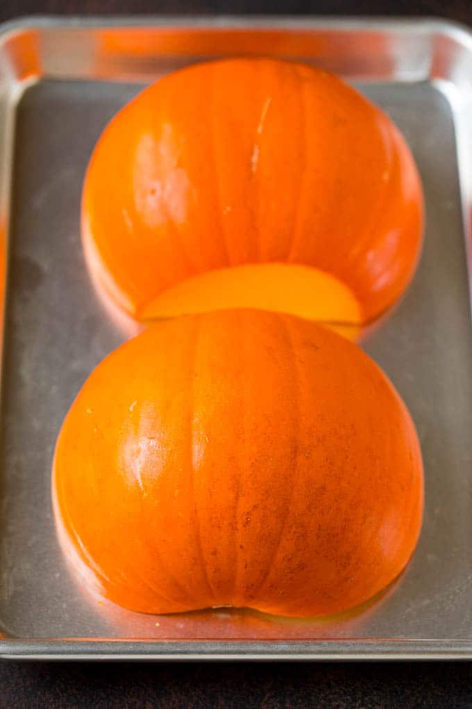 Pumpkin Puree Recipe #pumpkin #baking #fall #thanksgiving #edsug A pumpkin cut in half on a sheet pan.
