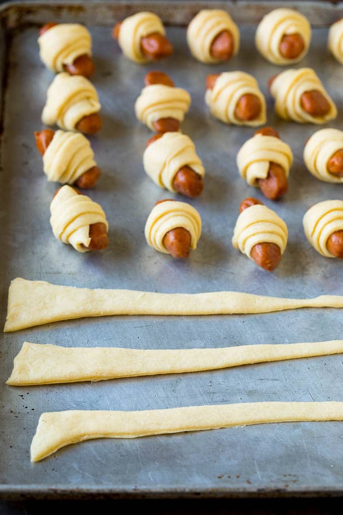 Pigs in a Blanket Recipe #hotdogs #appetizer #snack #comfortfood #edsug Strips of crescent dough on a sheet pan.