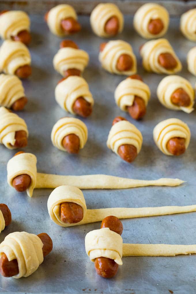 Pigs in a Blanket Recipe #hotdogs #appetizer #snack #comfortfood #edsug Hot dogs being rolled up in dough.