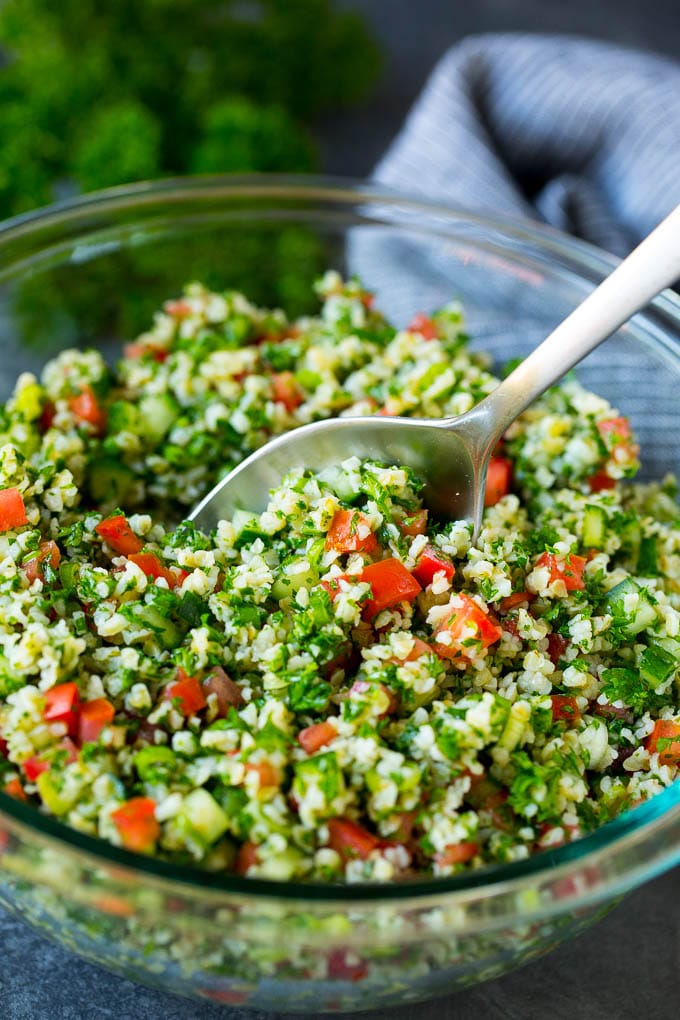 Tabbouleh Salad | Tabouli #salad #wheat #tomatoes #cucumber #healthy #sidedish #dinner #edsug A bowl of tabbouleh with a serving spoon in it.