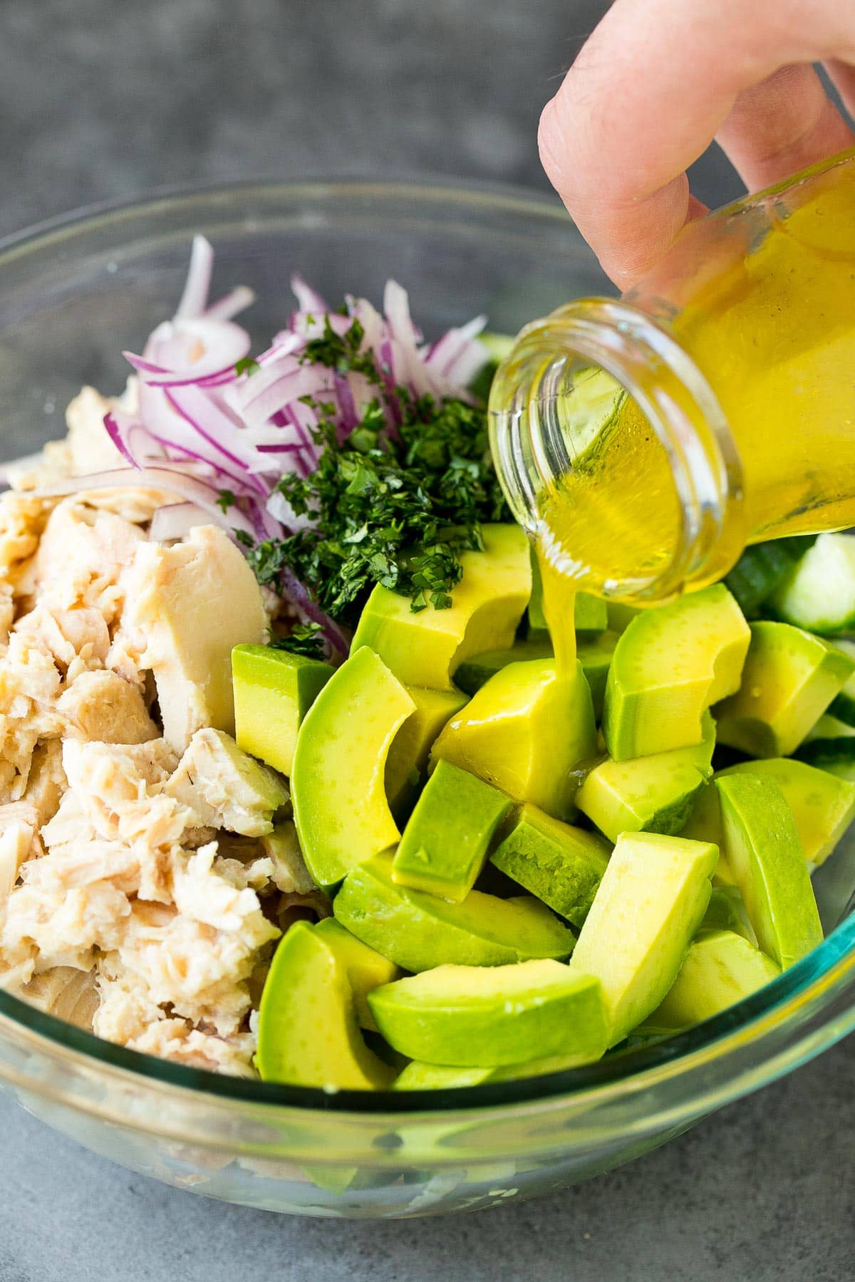 Dressing being poured into tuna salad.