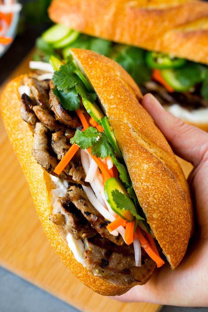 Bahn Mi Sandwich Recipe #sandwich #pork #lunch #dinner #edsug A hand holding a pork banh mi sandwich.