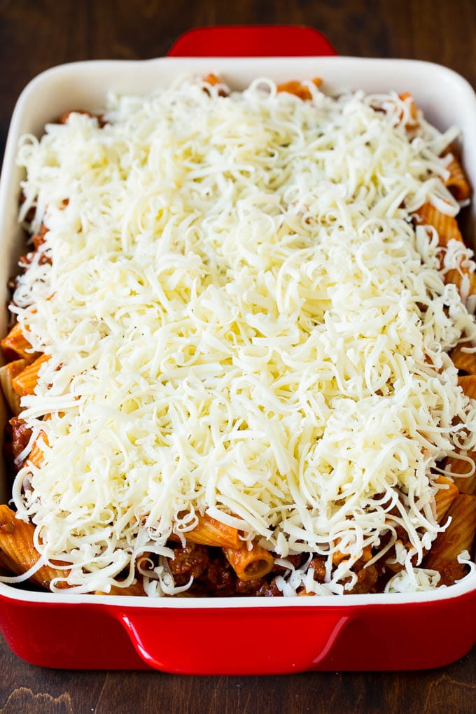 Baked Rigatoni Pasta #pasta #dinner #italianfood #groundbeef #edsug #casserole A pan of pasta in sauce topped with shredded cheese.