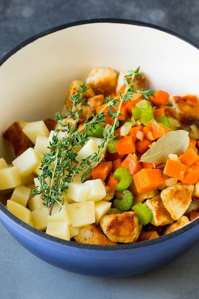 Chicken Pot Pie Soup Recipe | Chicken Soup #soup #chicken #dinner #comfortfood #edsug Ingredients such as vegetables, potatoes and herbs in a pot.