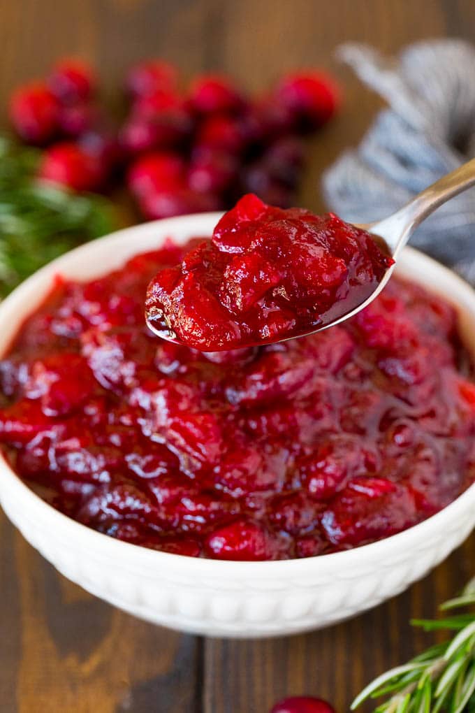 This homemade cranberry sauce is a 6 ingredient recipe that's made with fresh cranberries, sugar and a hint of spice. A spoon holding up a portion of homemade cranberry sauce.