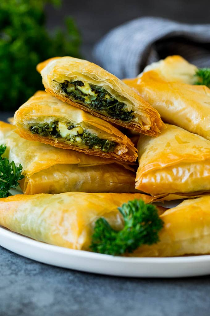 Spanakopita Recipe #appetizer #snack #spinach #cheese #edsug A plate of spanakopita with two cut in half.