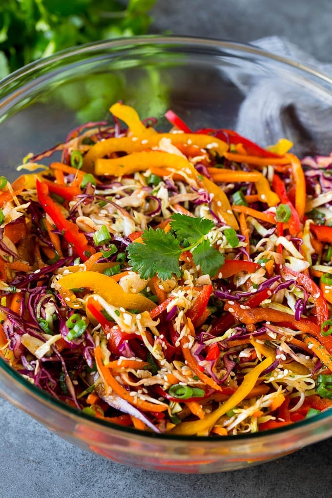 Asian Slaw Recipe #salad #slaw #sidedish #edsug A bowl of Asian slaw garnished with sesame seeds and herbs.