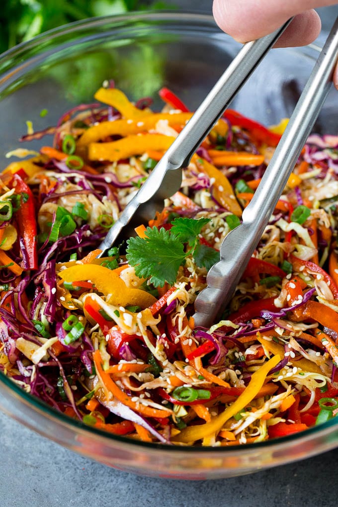 Asian Slaw Recipe #salad #slaw #sidedish #edsug Tongs serving up a portion of Asian slaw.