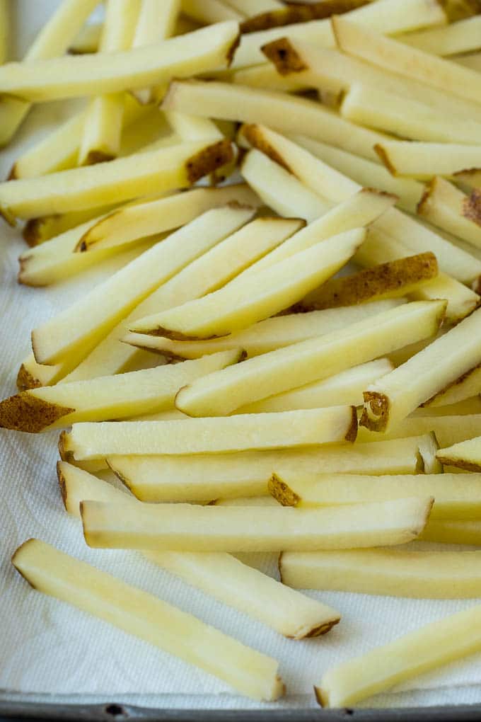 Homemade French Fries Recipe #potatoes #fries #dinner #edsug Potatoes cut into fry shapes on a paper towel lined pan.