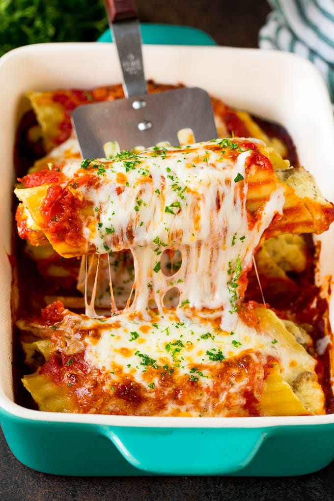 Baked Manicotti Recipe #pasta #cheese #dinner #edsug A spatula serving up a portion of baked manicotti pasta.