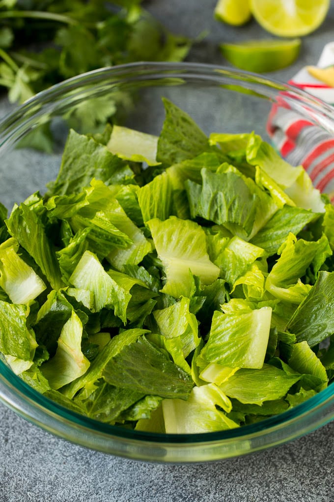 Mexican Salad Recipe #salad #corn #beans #avocado #tomatoes #edsug Chopped romaine lettuce in a bowl.