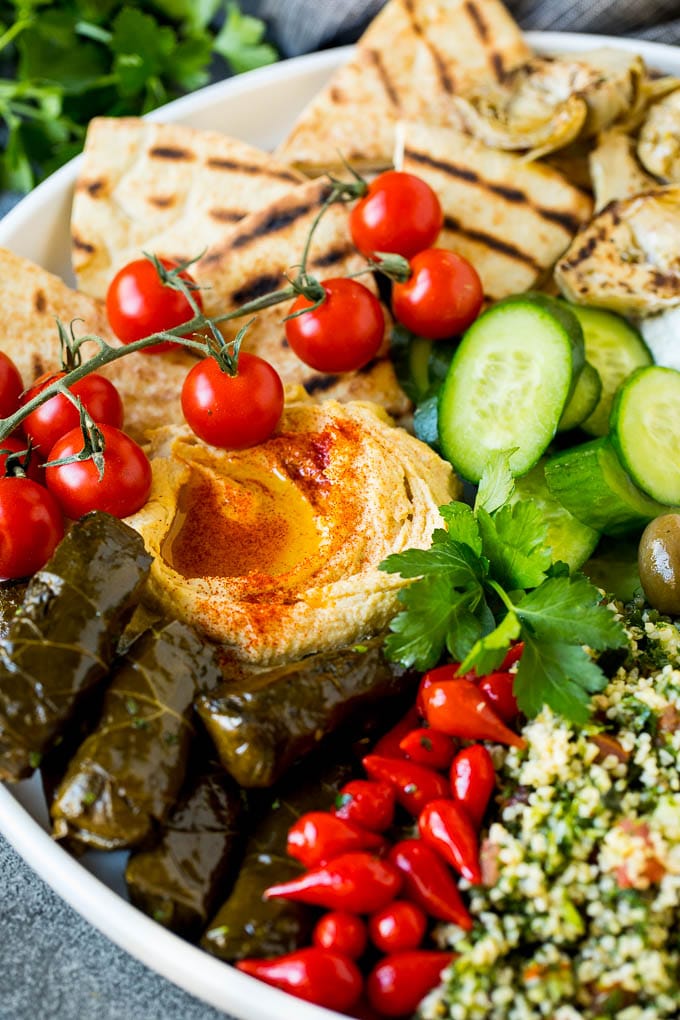 This mezze platter is filled with Mediterranean delicacies including dolmas, hummus, vegetables, pita bread and salads. #appetizer #edsug A Mediterranean mezze platter with hummus, dolmas and vegetables.