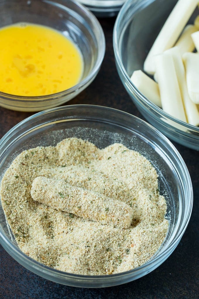 Mozzarella Sticks Recipe #cheese #appetizer #edsug Cheese in a bowl of seasoned breadcrumbs.