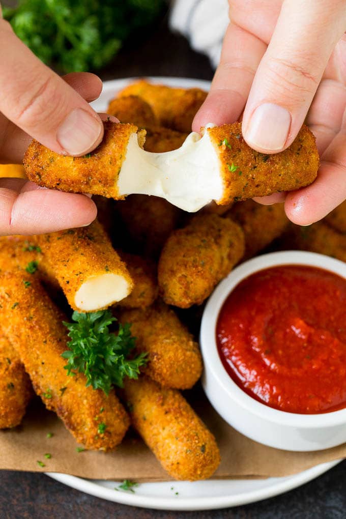 Mozzarella Sticks Recipe #cheese #appetizer #edsug A hand pulling apart mozzarella sticks.