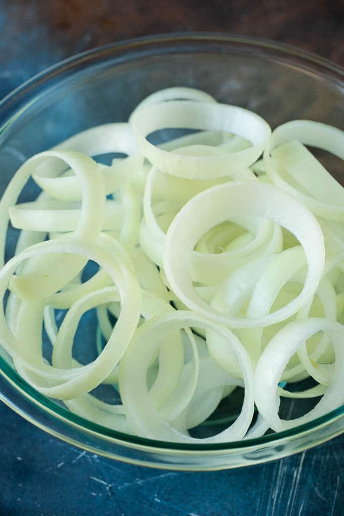 Crispy homemade onion rings that are fried in a flavorful beer batter. #onions #edsug #appetizer Raw onion slices in a bowl.