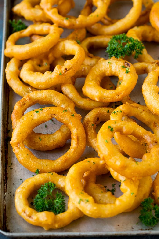 Crispy homemade onion rings that are fried in a flavorful beer batter. #onions #edsug #appetizer Beer battered onion rings on a sheet pan.