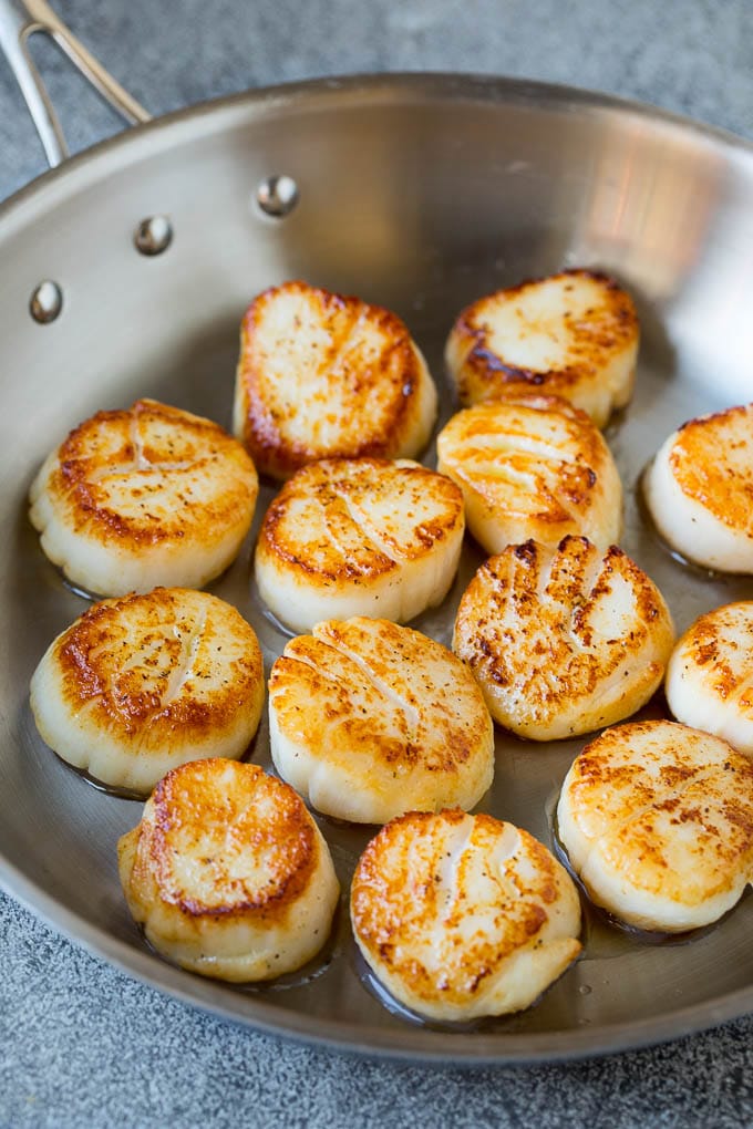 Seared scallops with a garlic and herb butter sauce. An easy and elegant dinner! #seafood #dinner #edsug Scallops cooked to golden brown in a pan.