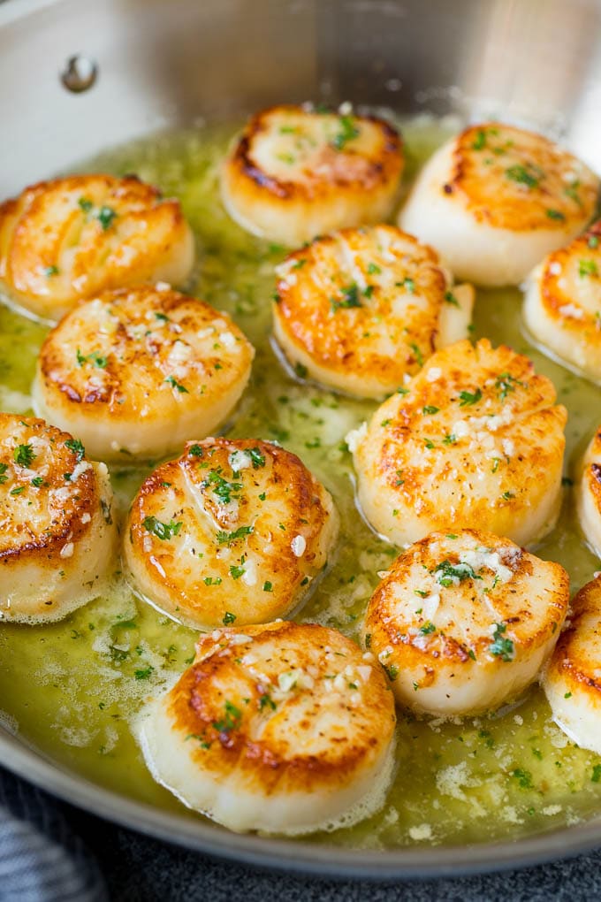 Seared scallops with a garlic and herb butter sauce. An easy and elegant dinner! #seafood #dinner #edsug A pan of scallops in garlic butter.