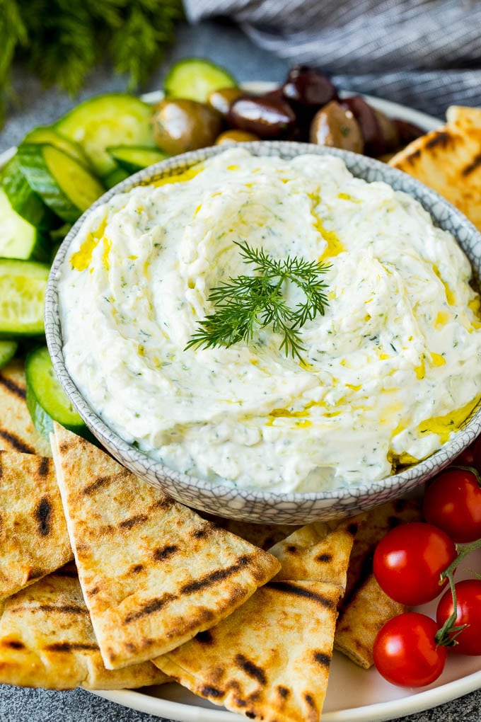 The best homemade tzatziki sauce with cucumber and herbs mixed into Greek yogurt. #appetizer #edsug A bowl of tzatziki served with pita bread and vegetables.