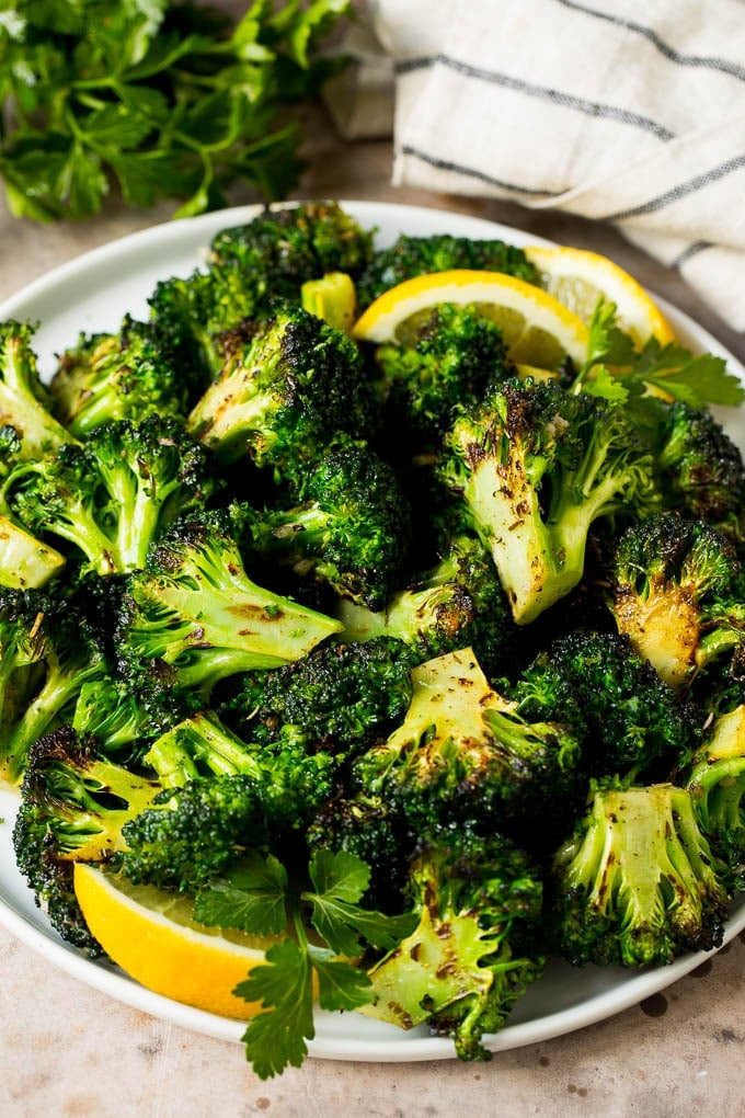 Grilled broccoli is packed with flavor and is a colorful and healthy side dish! #broccoli #edsug Grilled broccoli topped with parsley and garnished with lemon wedges.