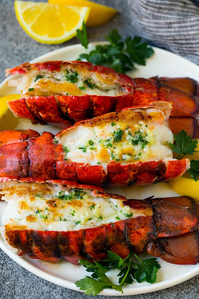 Grilled lobster tail drizzled with garlic butter is an easy and elegant dinner option. #lobster #edsug Grilled lobster tail topped with garlic butter and garnished with lemon and parsley.