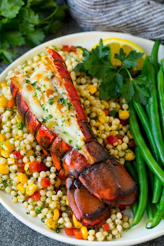 Grilled lobster tail drizzled with garlic butter is an easy and elegant dinner option. #lobster #edsug Grilled lobster tail served with couscous and green beans.