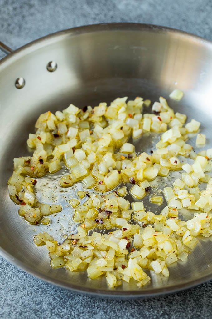 Sauteed kale flavored with olive oil and garlic, a quick and easy side dish! #kale #edsug Sauteed onions in a skillet.