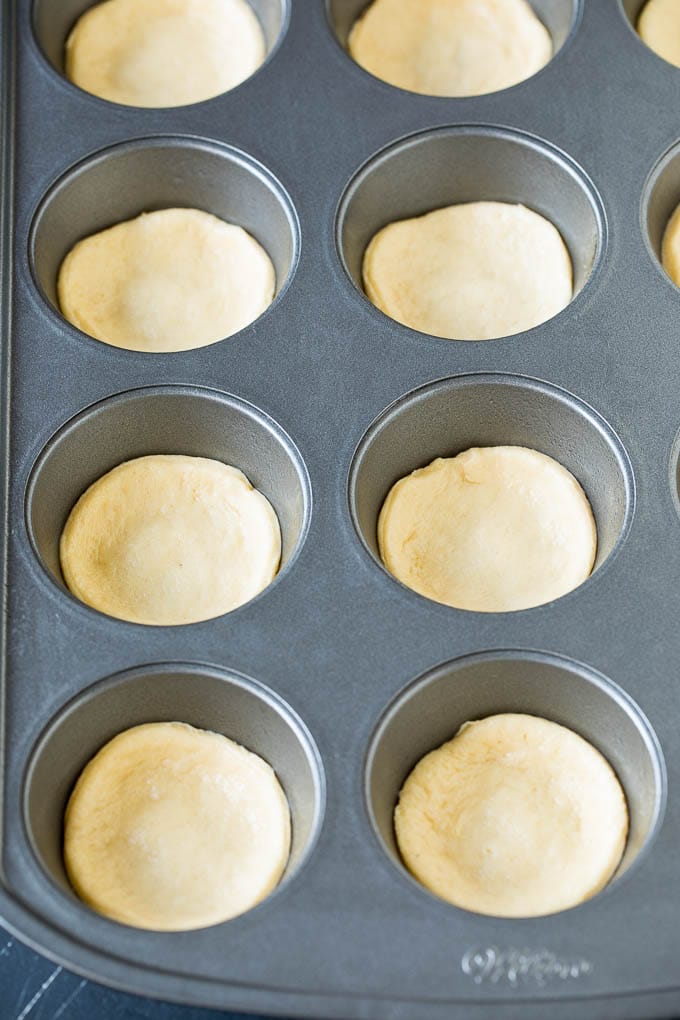 Mini pizzas topped with pepperoni are a fun and easy appetizer option. #pizza #edsug #appetizer Dough circles pressed into muffin cups.