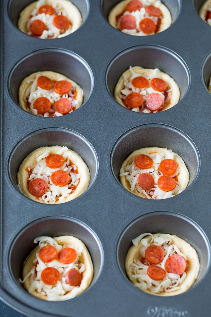 Mini pizzas topped with pepperoni are a fun and easy appetizer option. #pizza #edsug #appetizer Dough topped with sauce, cheese and mini pepperoni.