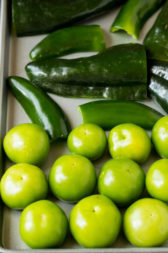 Tomatillos and chiles on a sheet pan.