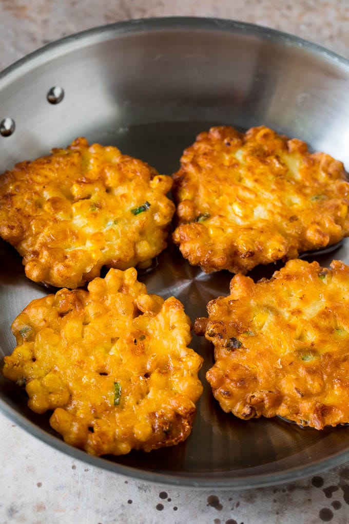 These crispy corn fritters are easy to make and are the perfect appetizer or lighter main course. #corn #edsug Corn cakes in a pan of oil.