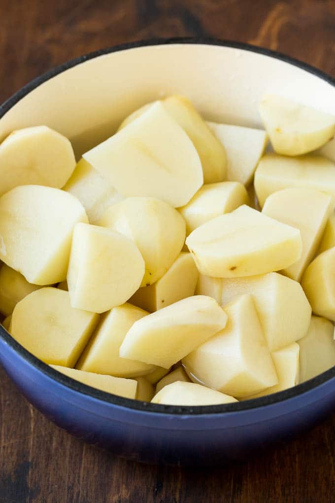 These cream cheese mashed potatoes are boiled potatoes blended with butter, milk, cream cheese and seasonings to make a rich and creamy side dish. Peeled potato quarters in a pot of water.