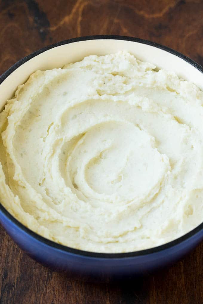 These cream cheese mashed potatoes are boiled potatoes blended with butter, milk, cream cheese and seasonings to make a rich and creamy side dish. Mashed potatoes in a blue pot.