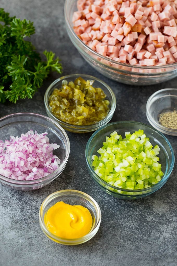 This ham salad is a blend of finely diced ham, mayonnaise, veggies and seasonings, all mixed together to form a savory and creamy salad. Bowls of diced meat, mustard, onion, celery and pickle relish.
