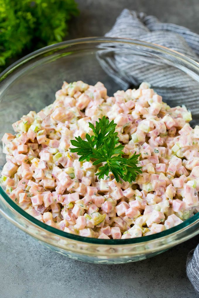 This ham salad is a blend of finely diced ham, mayonnaise, veggies and seasonings, all mixed together to form a savory and creamy salad. A bowl of creamy salad topped with parsley for garnish.