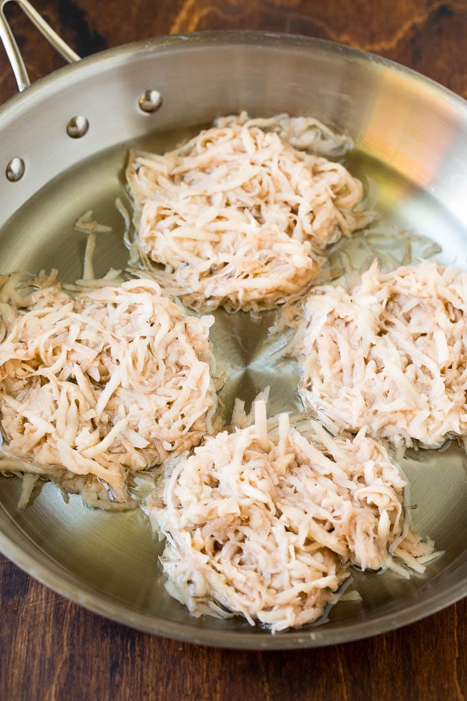 Shredded potato cakes in a pan of oil.