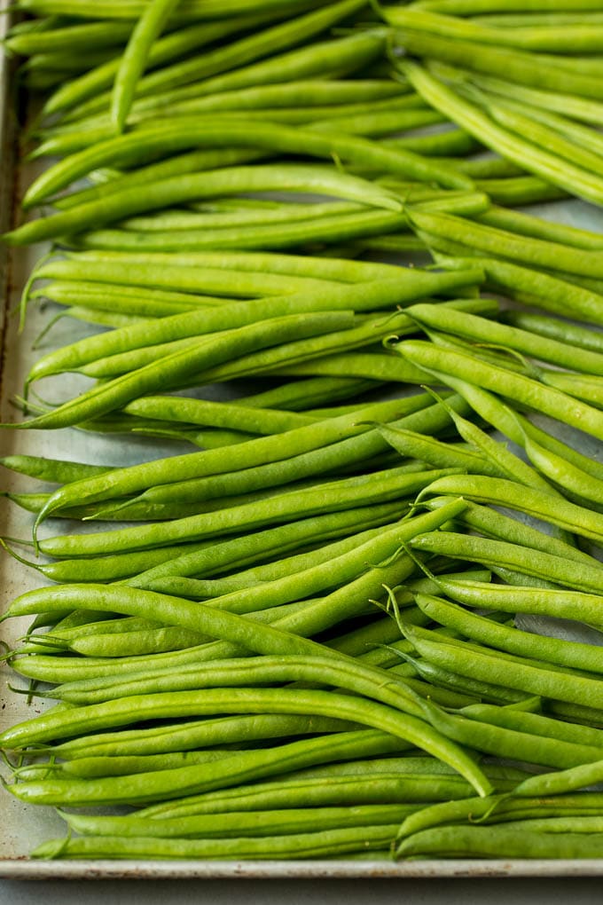 These sauteed green beans are cooked in butter, garlic and an assortment of fresh and dried herbs. Raw green beans on a sheet pan.