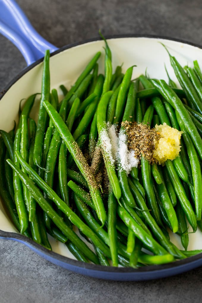 These sauteed green beans are cooked in butter, garlic and an assortment of fresh and dried herbs. Beans with garlic and seasonings in a pan.