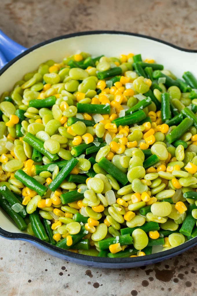 This succotash recipe is a combination of bacon, corn, tomatoes and lima beans, all cooked together to make a colorful and delicious side dish. Corn, lima beans and green beans in a skillet.