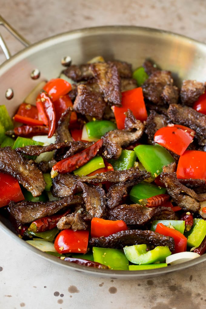 This Szechuan beef is a spicy stir fry made with tender pieces of beef and colorful vegetables, all tossed in a sweet and savory sauce. Steak, peppers and onions cooked in a pan.