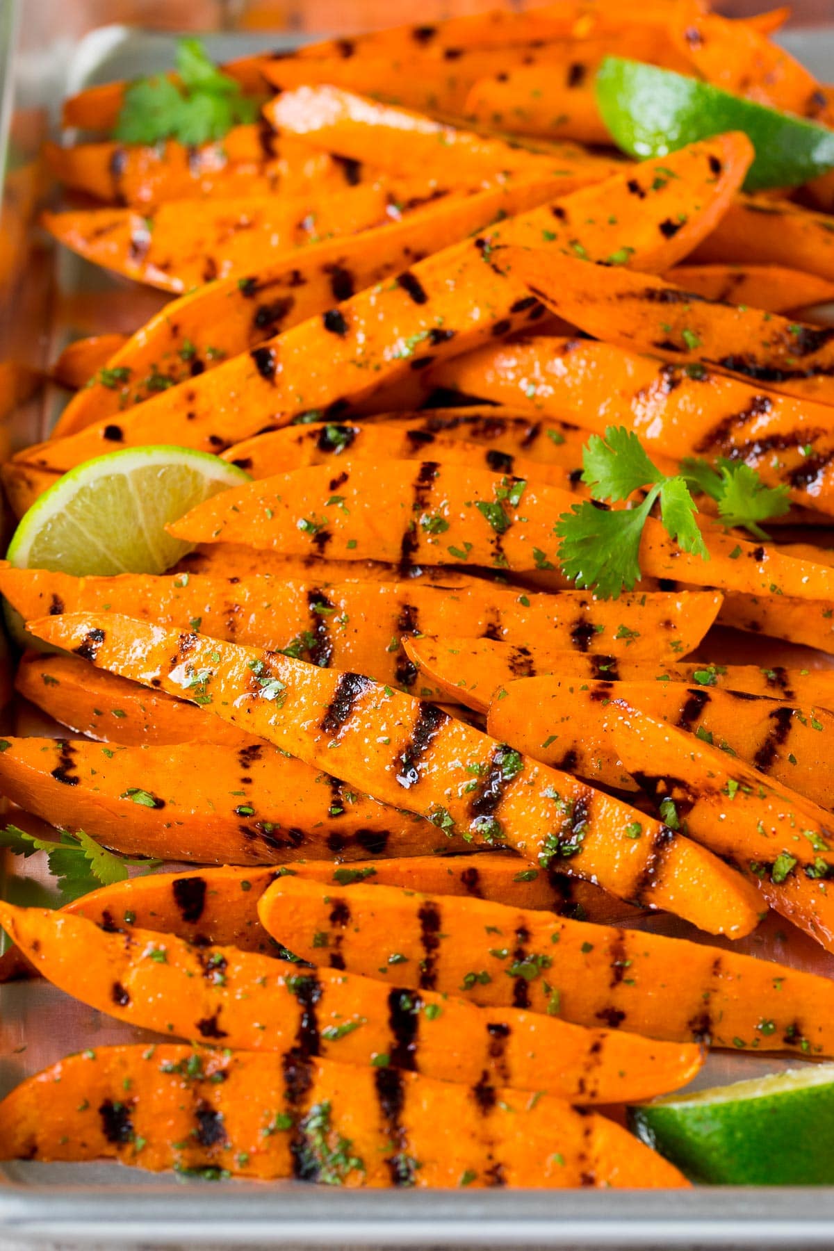 A sheet pan of grilled sweet potatoes garnished with lime and cilantro.